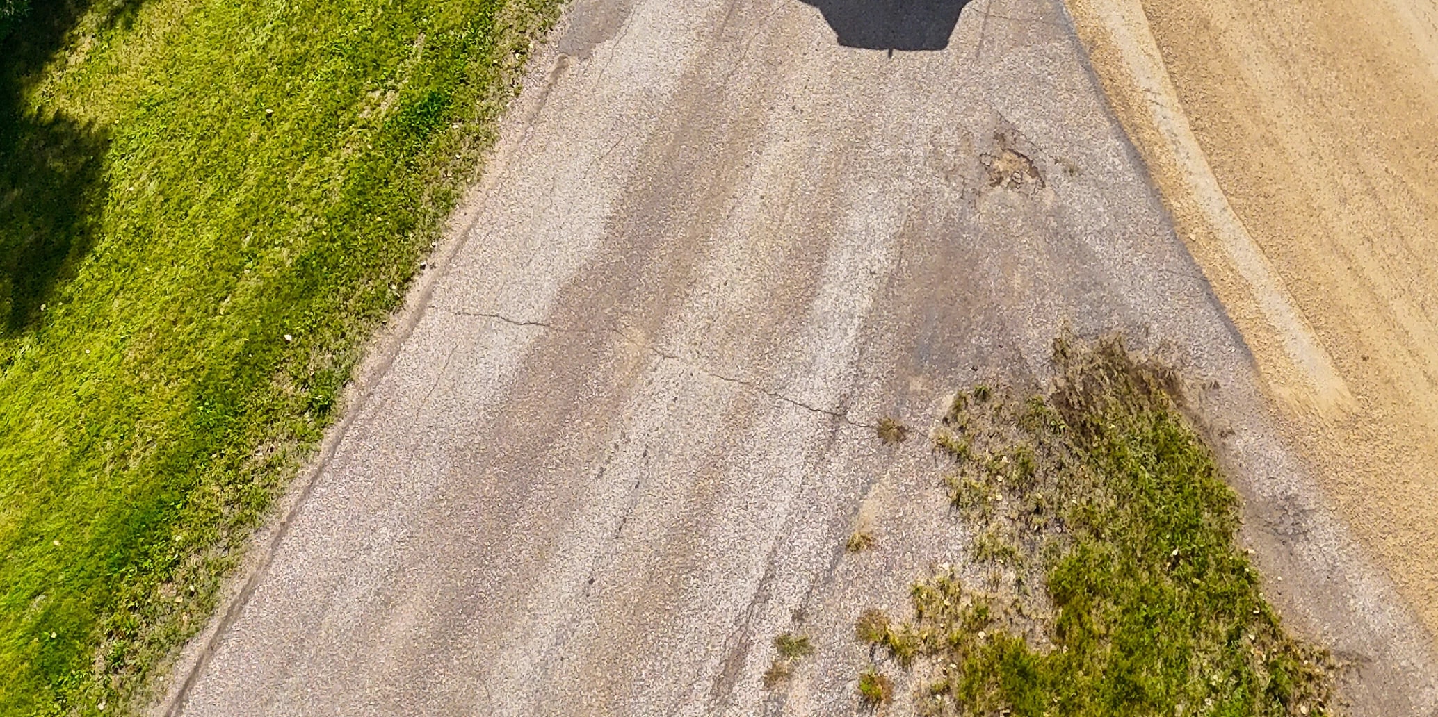 Close-up from above of an aging asphalt road with cracks running across the surface